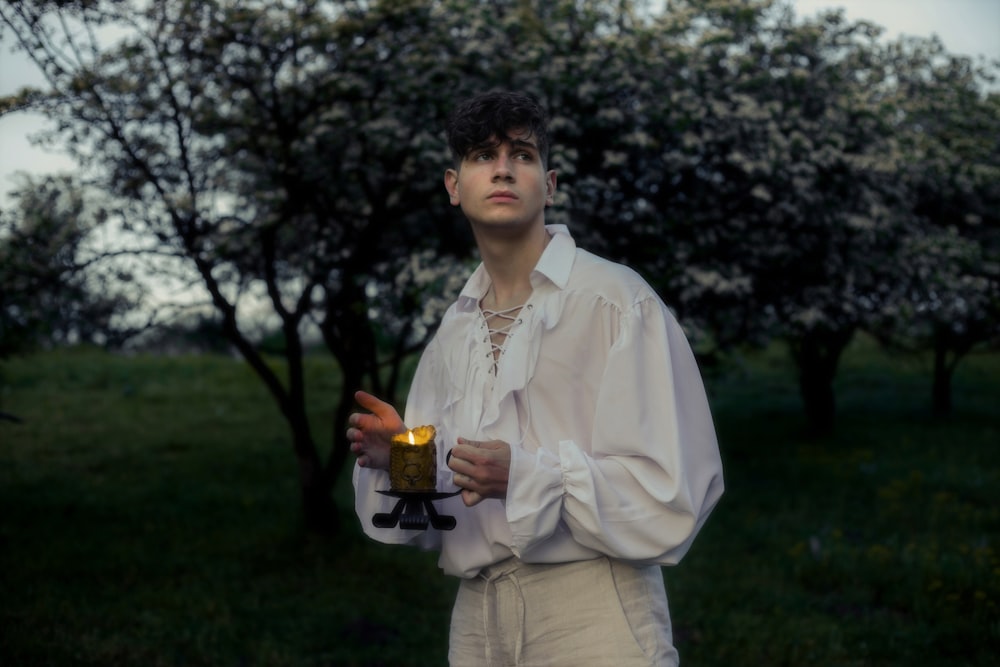 a man in a white shirt holding a lit candle