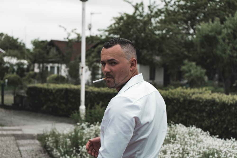 a man in a white shirt smoking a cigarette