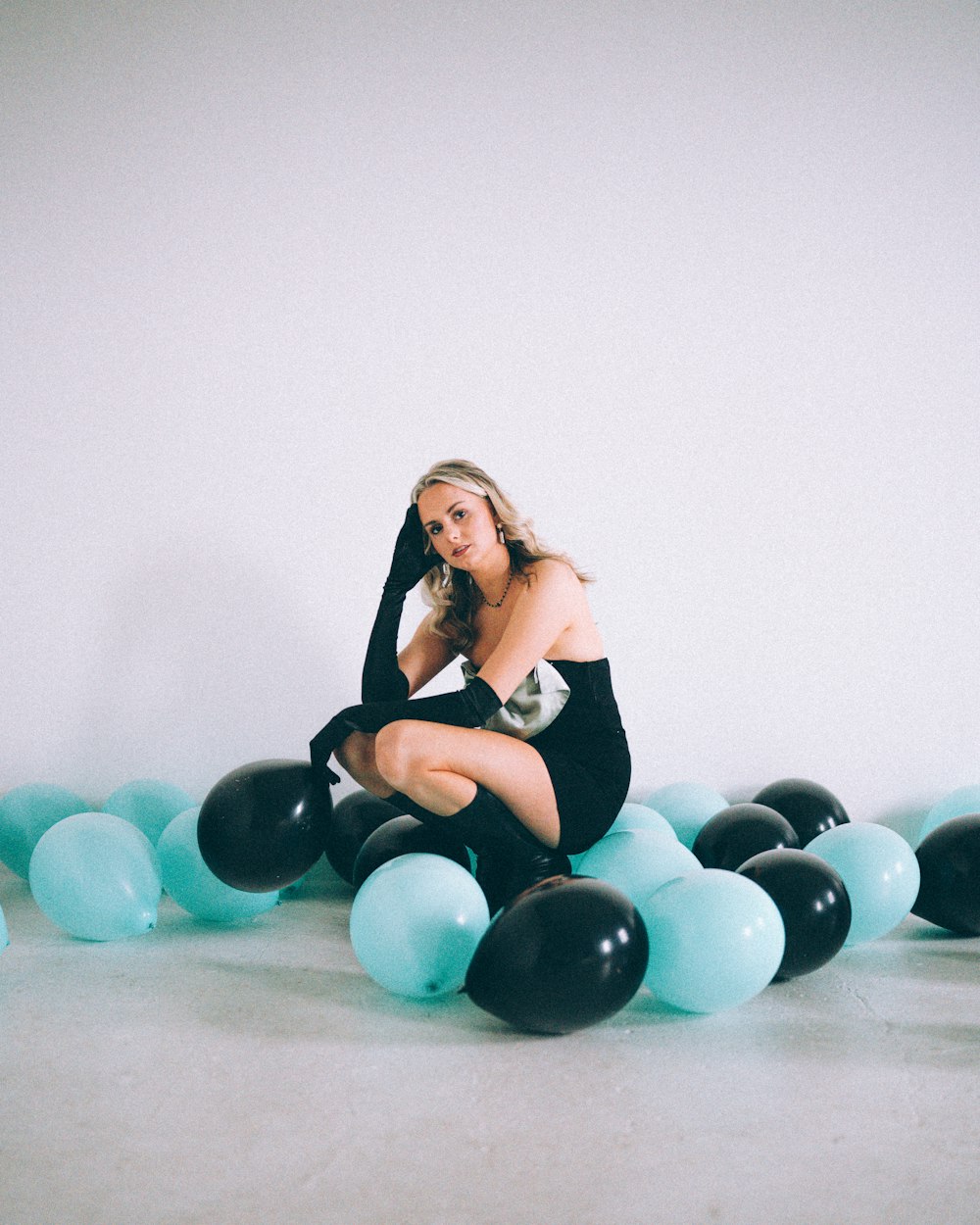 a woman sitting on the ground surrounded by balloons