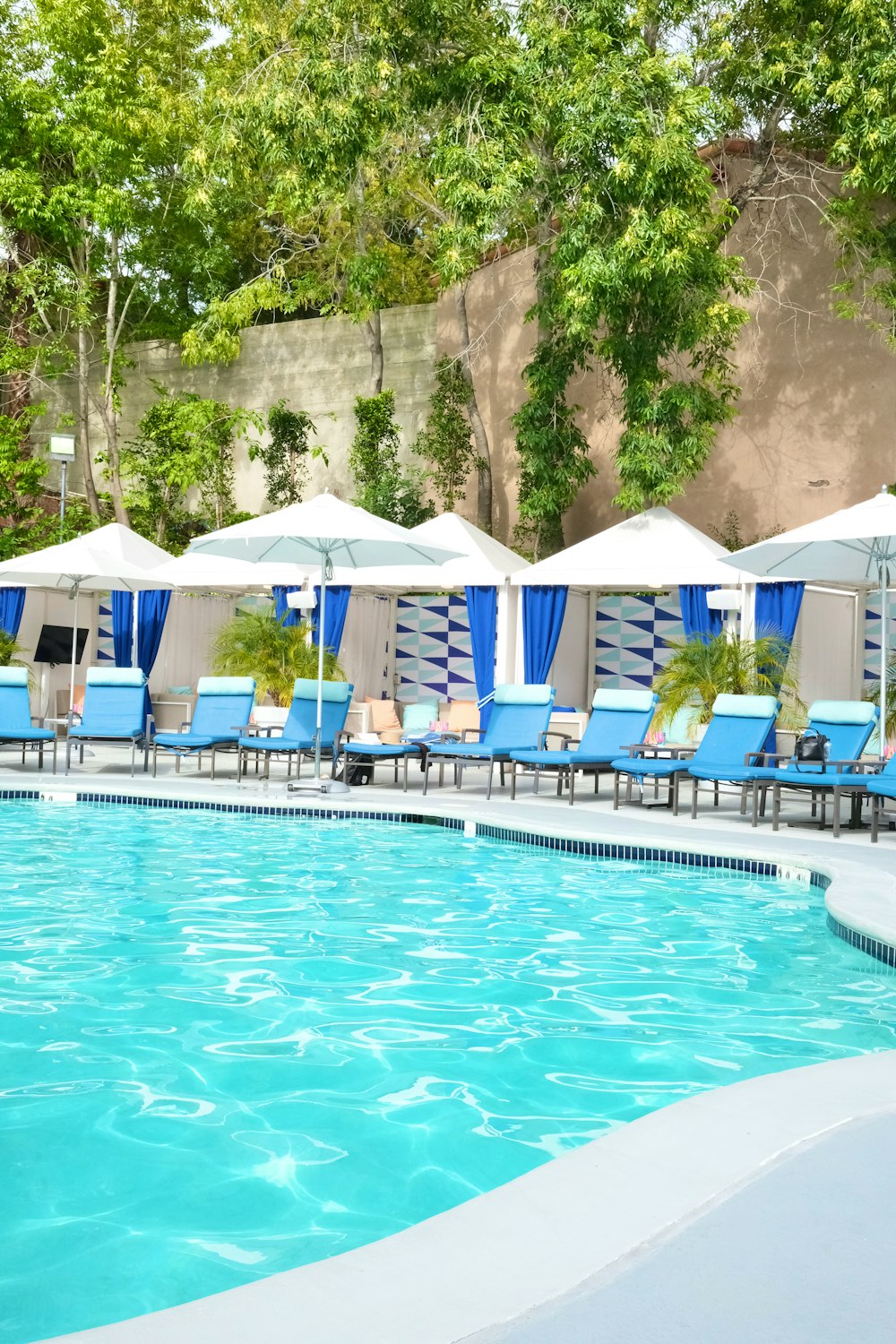 a large swimming pool with chairs and umbrellas