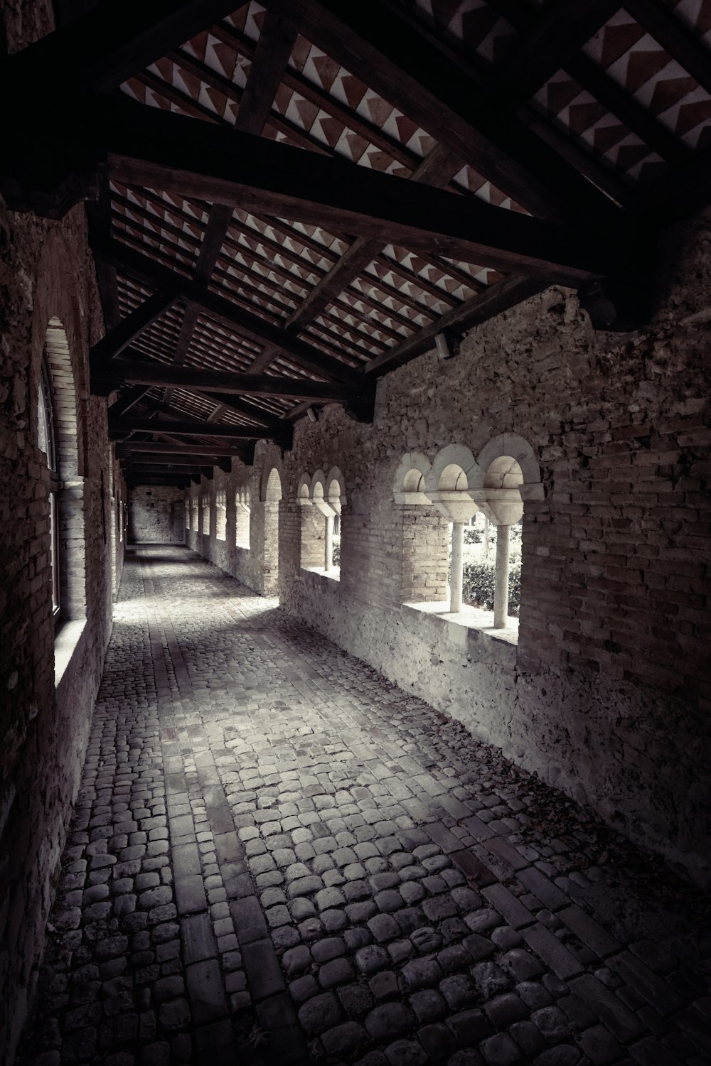 a dark alley with brick walls and arched windows