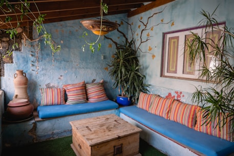 a living room with a blue couch and potted plants