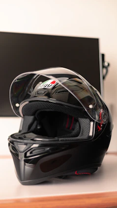 A sleek motorcycle helmet displayed on a simple wooden shelf with a neutral background.