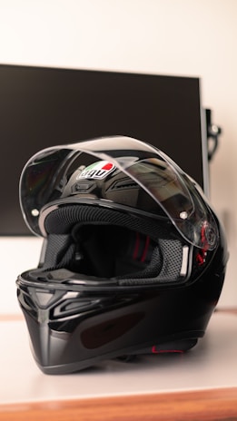 A sleek black motorcycle helmet resting on a wooden table with a blurred city background.