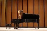 a black piano sitting in front of a wooden wall