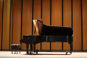 a black piano sitting in front of a wooden wall