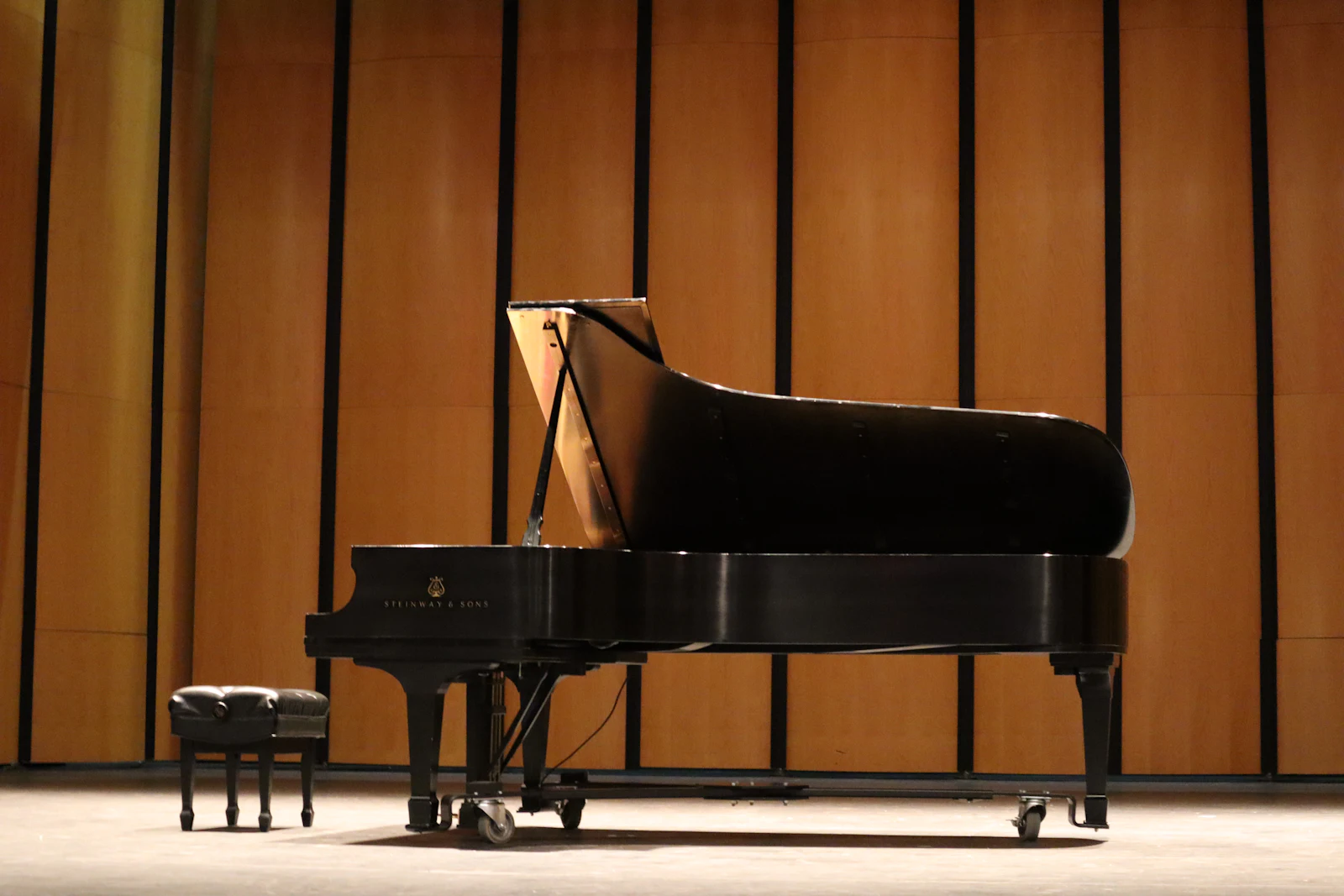 A black piano in front of a wooden wall