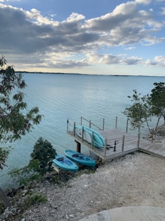 A peaceful lakeside retreat with a wooden dock and kayaks resting on the shore.