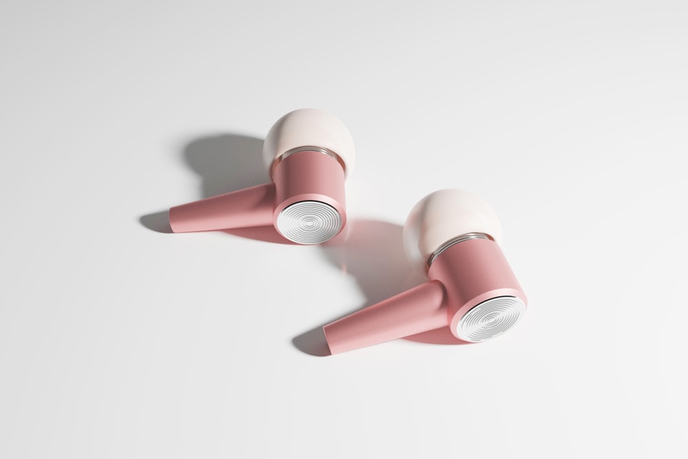 a pair of pink earphones sitting on top of a white surface