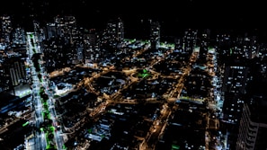 Nighttime aerial view of a sophisticated urban development with illuminated streets