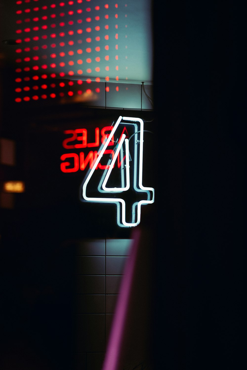 a neon sign that reads 4 while sitting on a wall