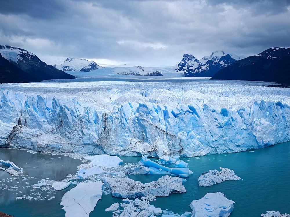 a large glacier with mountains in the background