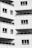 Multiple balconies with glass railings and a modern design style, featuring clean lines and grid patterns. The surface material appears to be a white or light-colored panel.