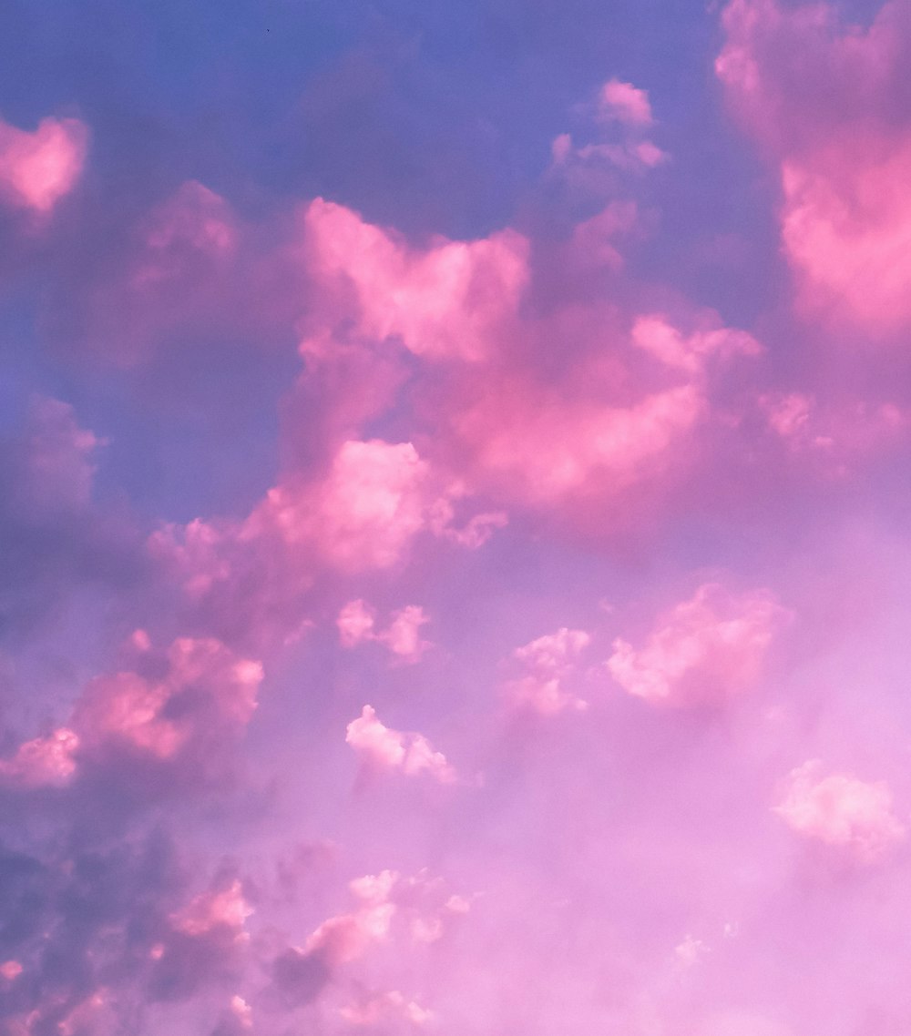 a plane flying in the sky with pink clouds