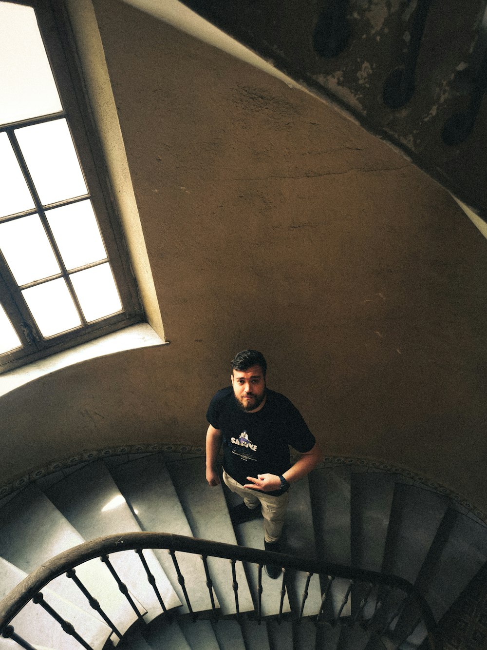 a man standing at the top of a spiral staircase