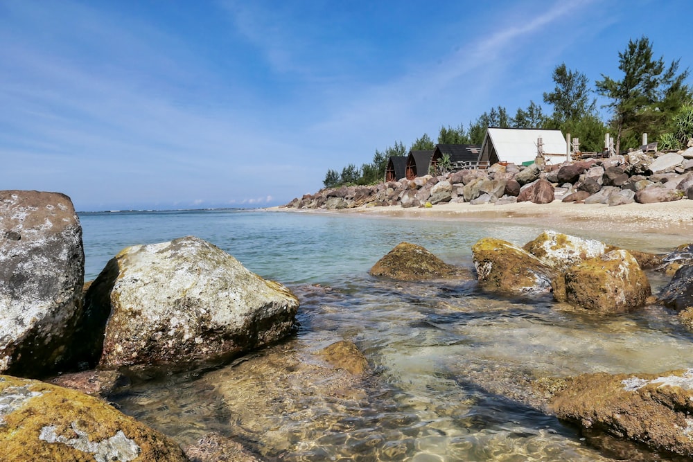 a beach with rocks and a house in the background