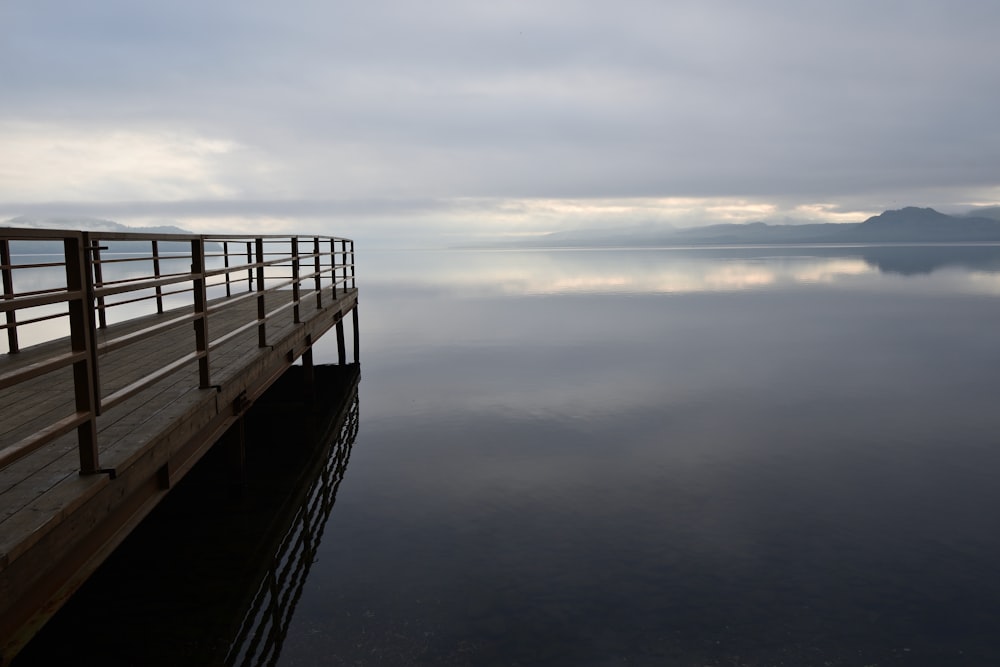 a wooden dock sitting on top of a lake under a cloudy sky