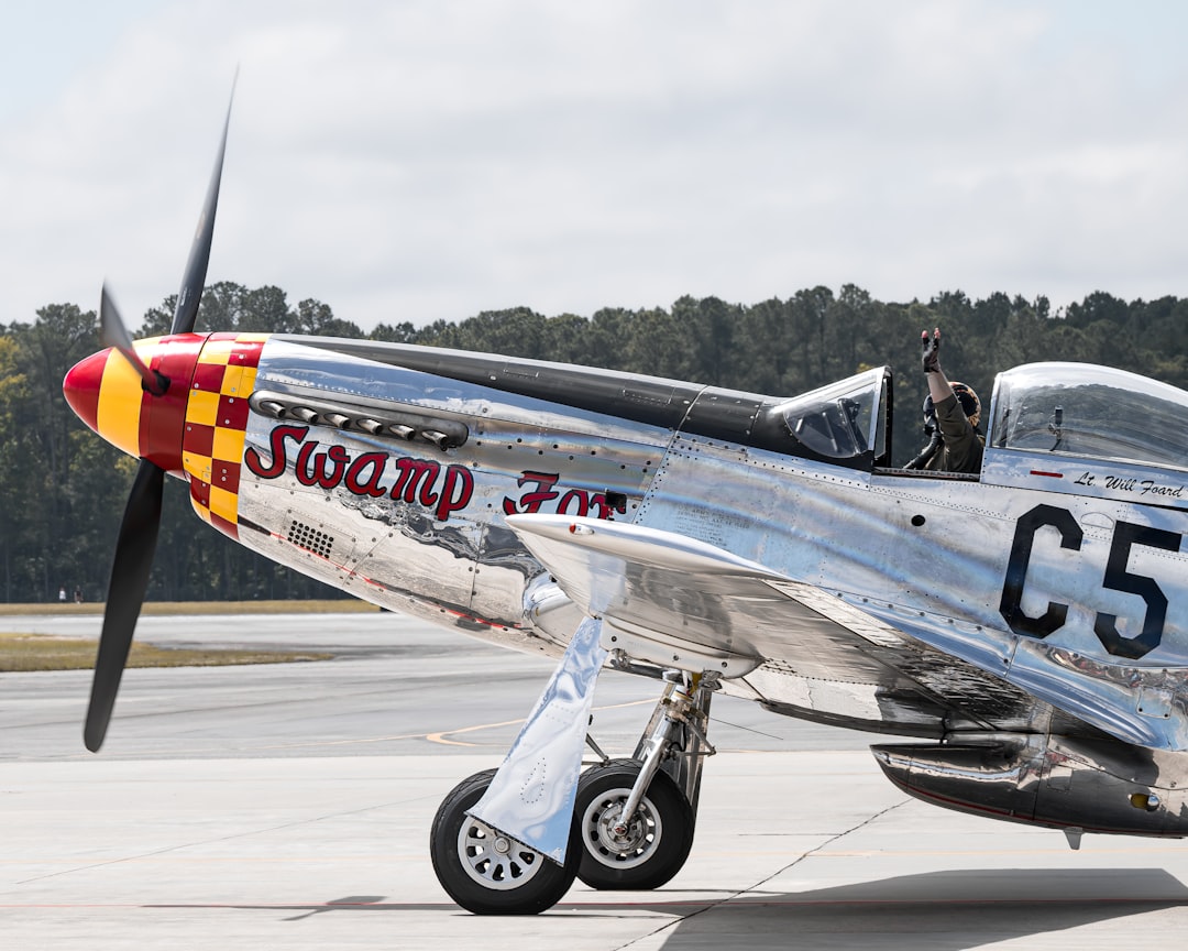 a silver and red airplane sitting on top of an airport tarmac, P51 Mustang