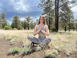 A peaceful outdoor scene with a person sitting quietly, praying or meditating in nature.