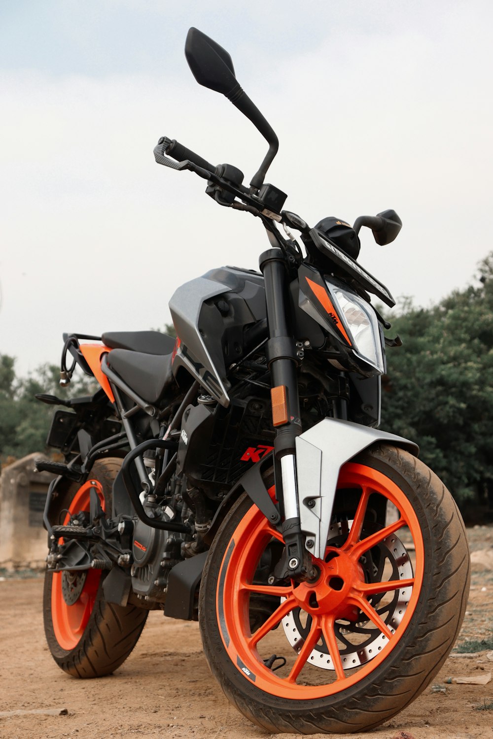 a black and orange motorcycle parked on a dirt road