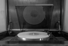 A vinyl record spinning on a turntable surrounded by scattered lyric sheets