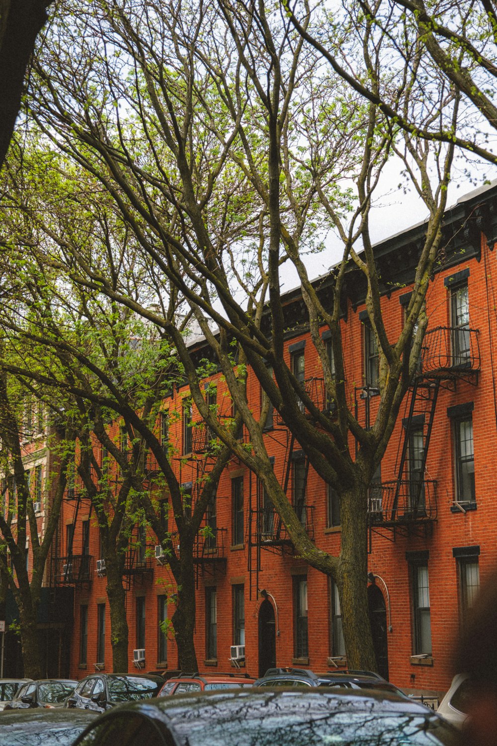 a row of red brick apartment buildings with cars parked in front of them