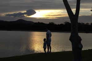 A candid shot of the daughter leaning on her father’s shoulder during a peaceful lakeside stroll.