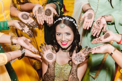 A vibrant mehendi ceremony scene with colorful drapes and joyful guests applying henna.