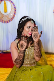 a woman in a green dress holding her hands up to her face