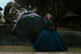 a woman in a blue dress standing in front of a large black object