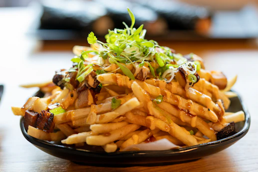 a plate of french fries with sauce and sprouts