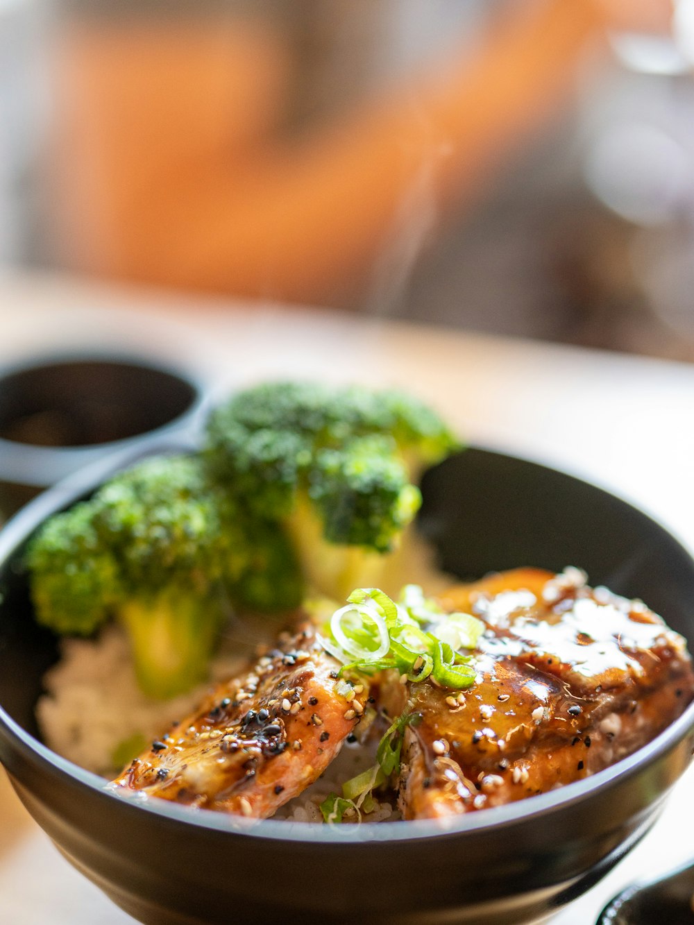 a black bowl filled with meat and broccoli