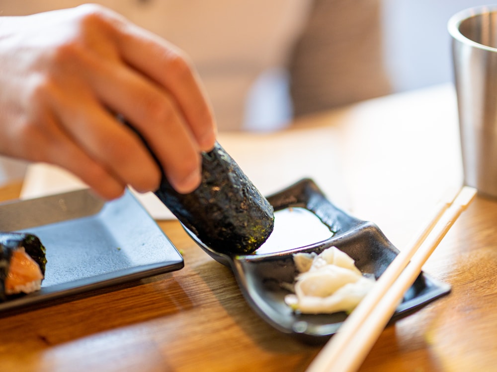 a person eating sushi with chopsticks on a table