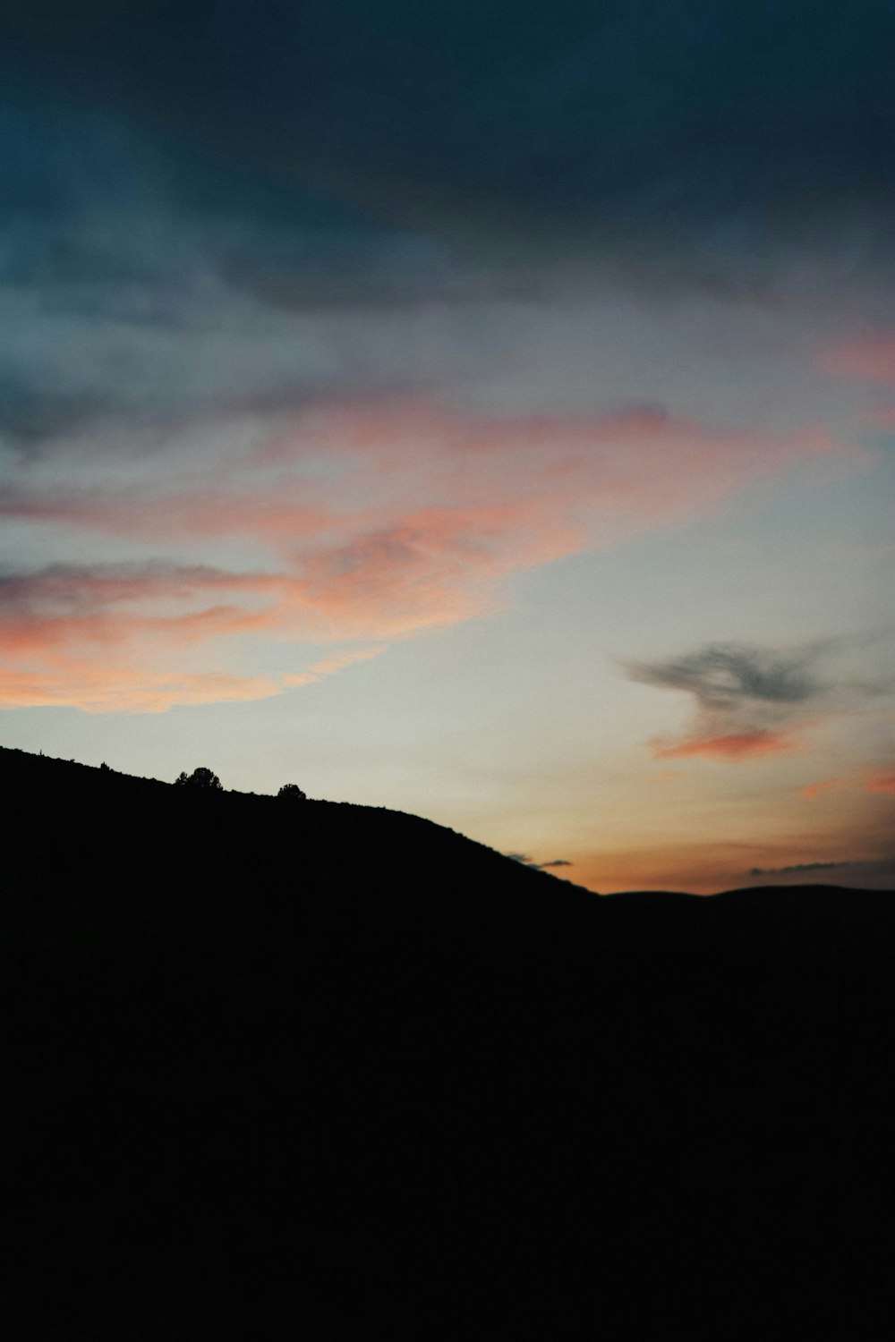 a silhouette of a person standing on top of a hill