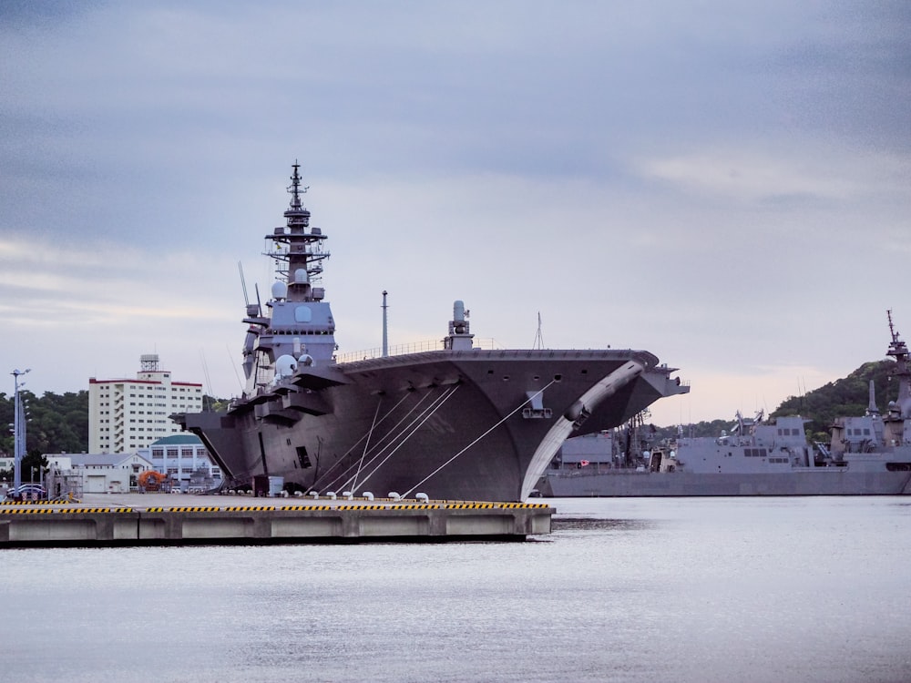 a large military ship docked in a harbor