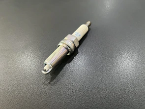 A set of car spark plugs neatly arranged with a promotional banner in the background