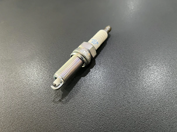 Close-up of shiny new spark plugs displayed in rows on a retail shelf