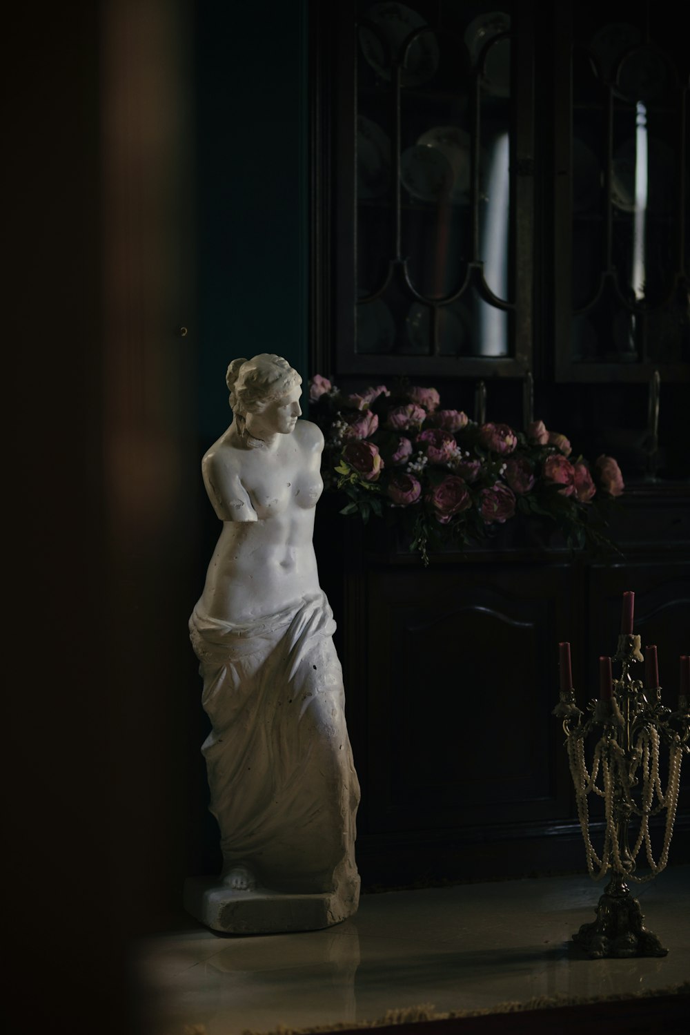 a statue of a woman standing next to a vase of flowers