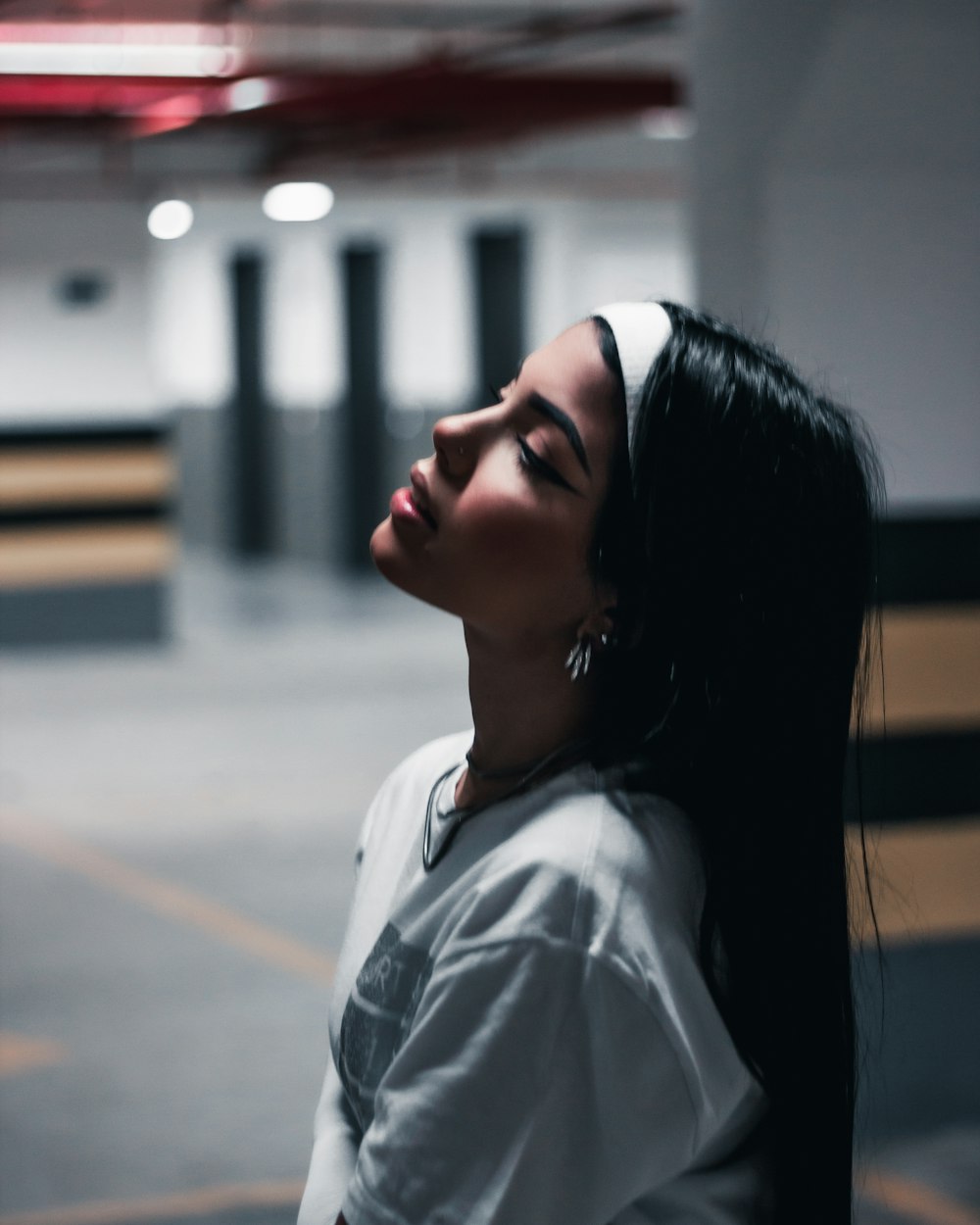 a woman with long black hair standing in a parking garage