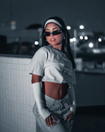 A stylish fashion model posing confidently in an urban setting with dramatic lighting.