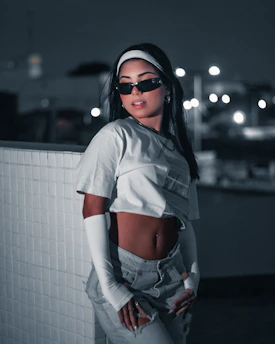 A stylish fashion model posing confidently in an urban setting with dramatic lighting.