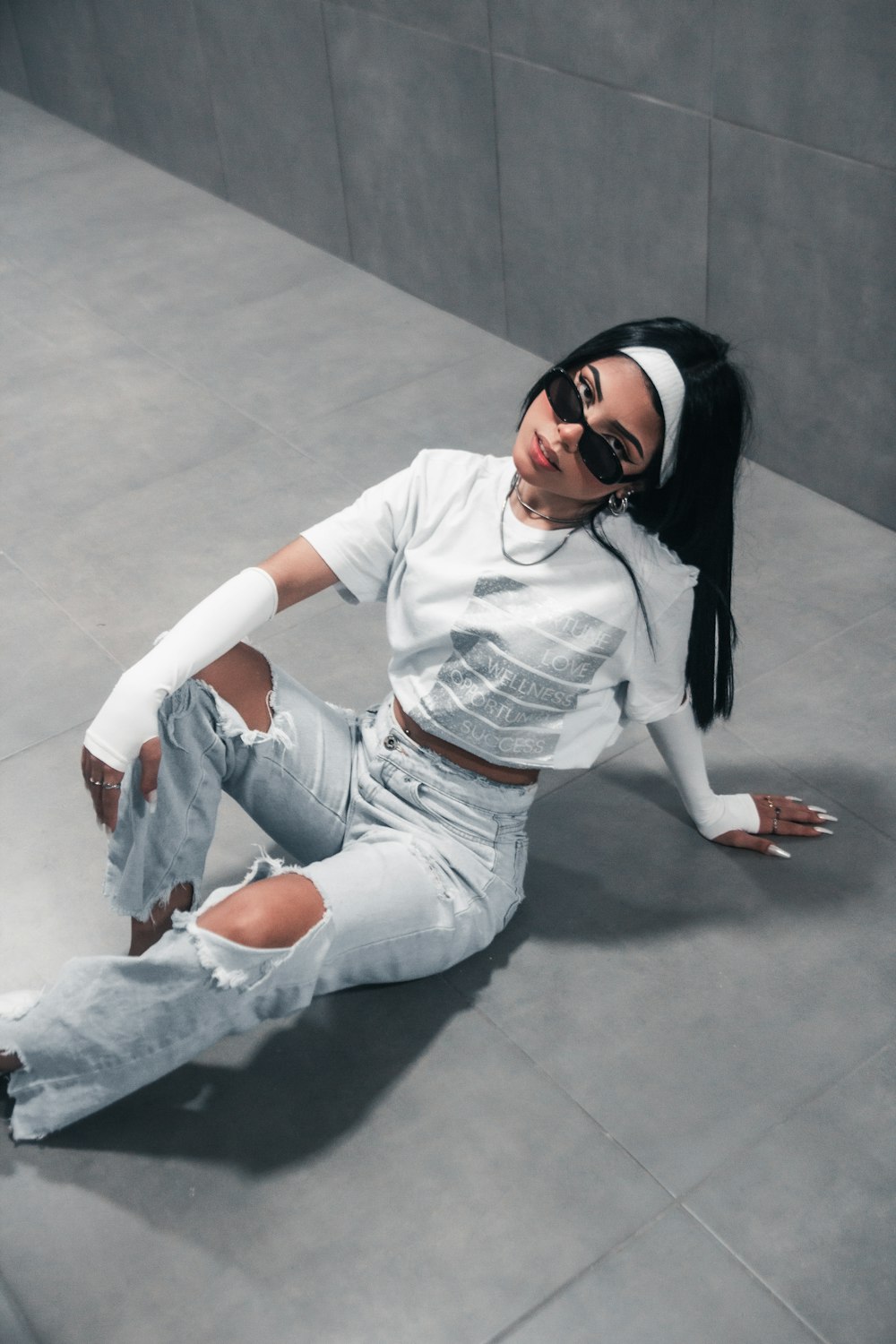 a woman in white shirt and jeans laying on the ground