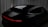 A sleek, dark-colored car is angled from the rear, showcasing its smooth curves and modern design. The setting includes a dimly lit environment with vertical draped fabrics contrasting against the vehicle's glossy surface. A sharp, continuous red light strip runs across the back, adding a futuristic touch.