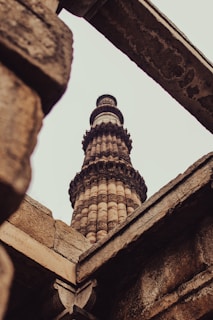 The delicate carvings of Qutub Minar subtly visible behind a stack of ancient language texts.