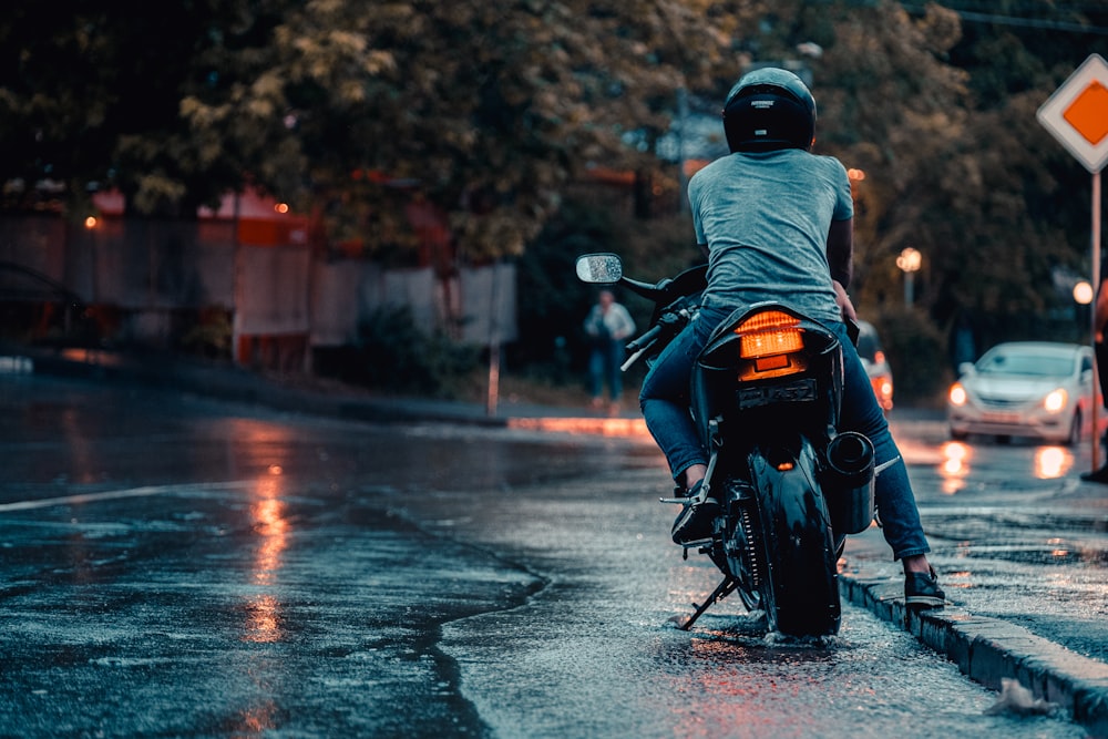a man riding a motorcycle down a wet street
