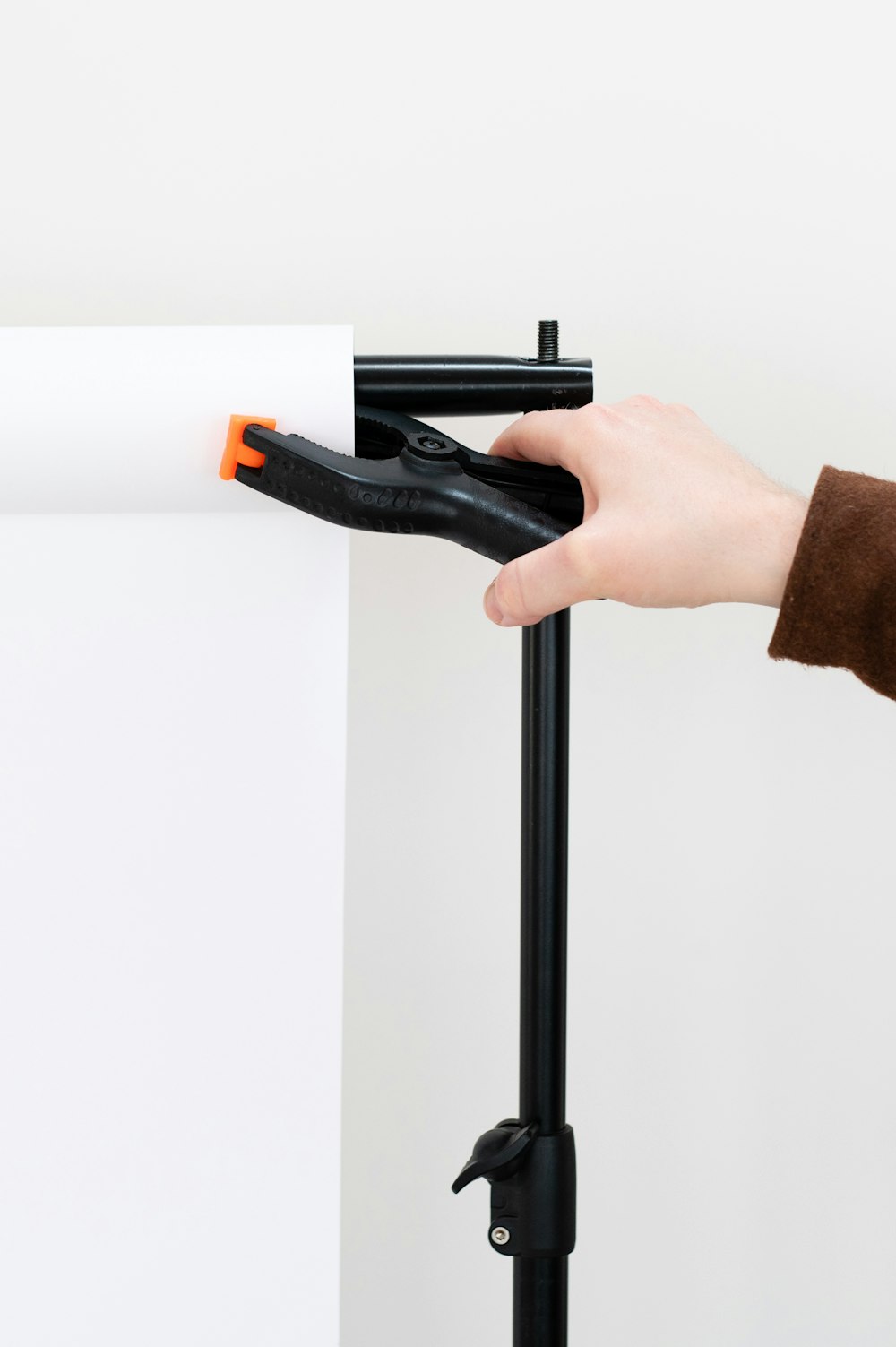 a hand holding a piece of paper with a black handle