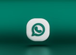A three-dimensional icon resembling the logo of a chat application, featuring a white speech bubble with a green telephone handle inside. The icon is set against a gradient green background and appears to be floating.
