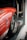 A red sports car is securely fastened inside a trailer. The focus is on the rear section, highlighting the sleek metallic wheel and tire. Visible branding and sponsor logos add a racing aesthetic to the scene.