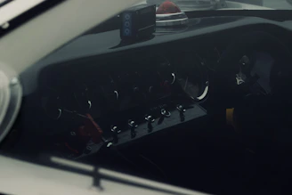 Close-up of a car dashboard warning light glowing red in a dimly lit garage.