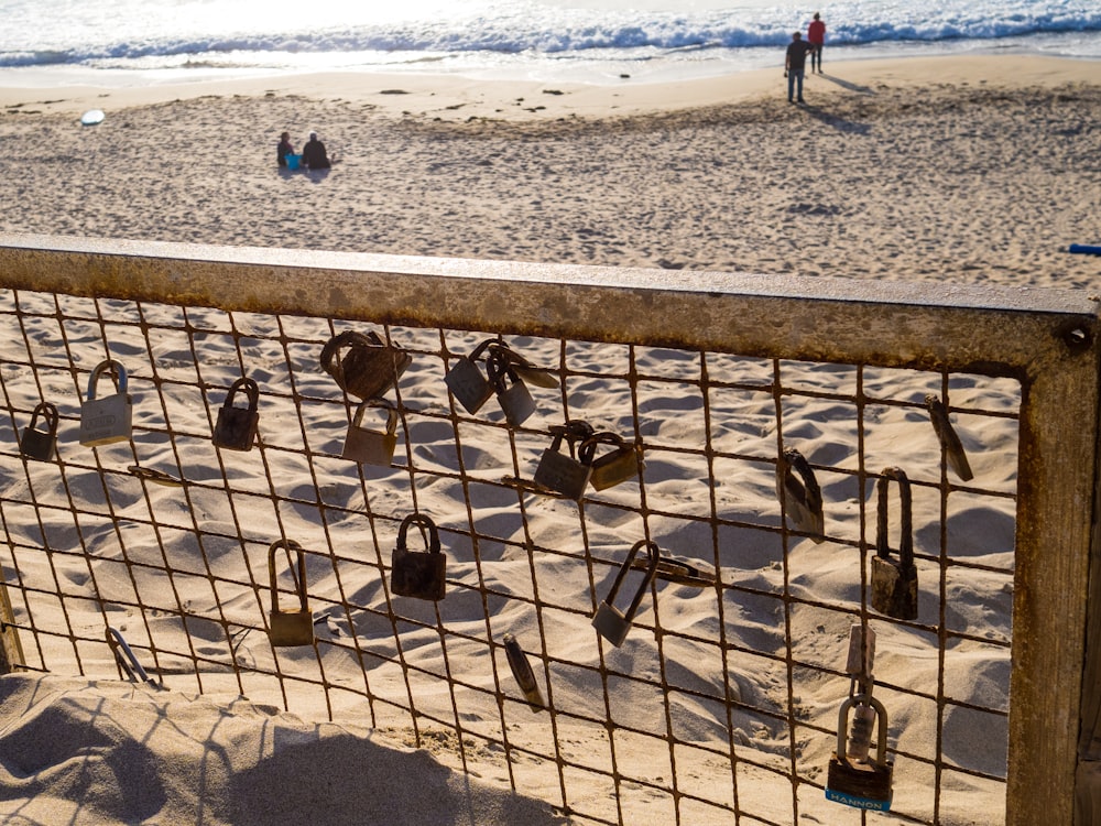 a fence on a beach with people walking on the beach in the background